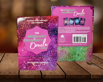 May include: A pink and purple oracle card deck box with the text "The Abundance & Prosperity Oracle Cards" and "Enchanted Empress Tarot". The back of the box shows a green and blue background with the text "The Abundance & Prosperity Oracle Cards" and a barcode.