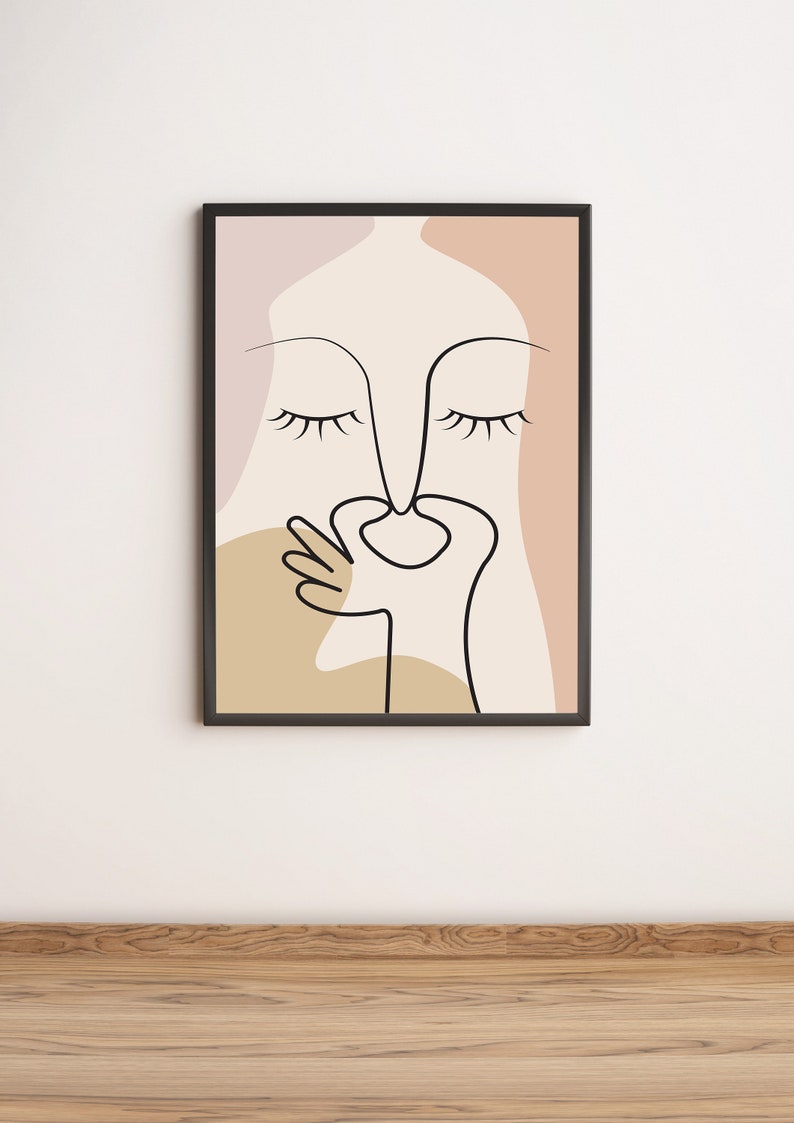Peut inclure: Une impression encadr&eacute;e en noir avec un dessin au trait d'un visage aux yeux ferm&eacute;s et une main couvrant le nez. L'arri&egrave;re-plan est un m&eacute;lange de rose, beige et marron.