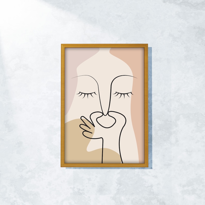 Peut inclure: Une impression d'art abstrait encadr&eacute;e avec un dessin de ligne minimaliste d'un visage aux yeux ferm&eacute;s et une main couvrant le nez et la bouche. L'arri&egrave;re-plan est de couleur rose et beige.