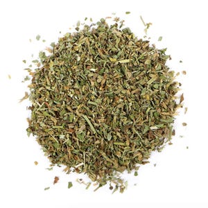 May include: A pile of dried herbs, predominantly green with lighter brown and tan hues, against a white background. The herbs appear to be finely chopped and have a textured appearance, suggesting a culinary ingredient.