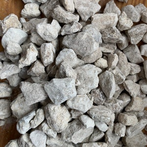May include: A pile of small, white, and gray rocks. The rocks are irregularly shaped and have a rough texture.