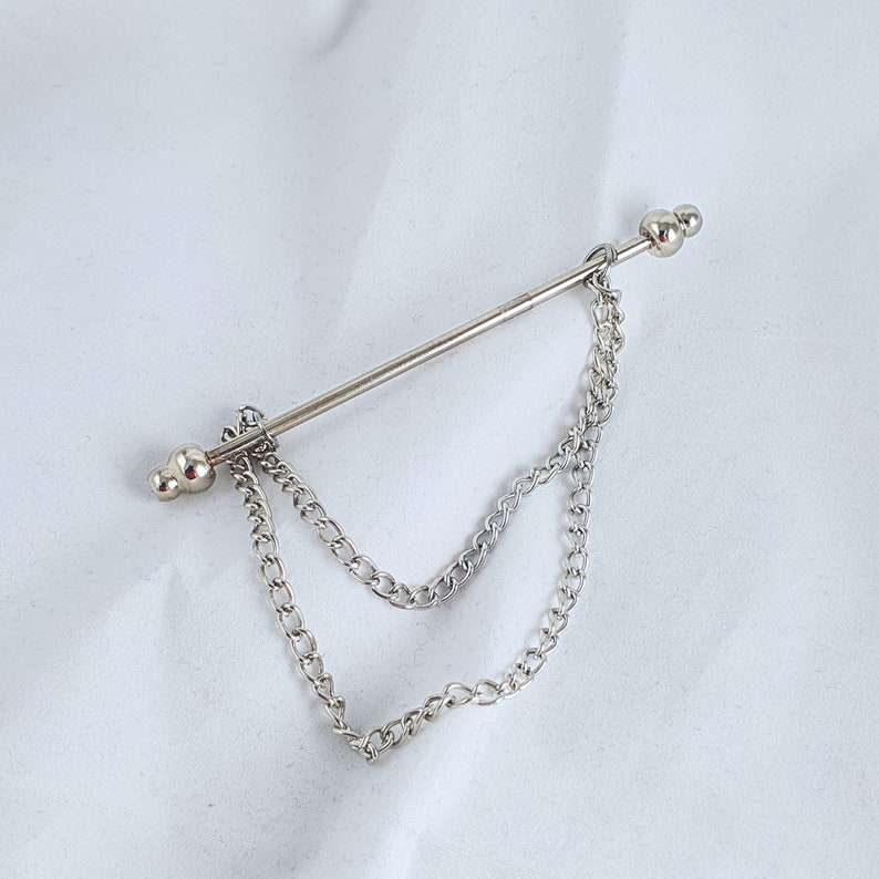 Op de afbeelding: Zilveren stropdasgesp met een dubbele ketting. De ketting is bevestigd aan een zilveren staaf met twee ronde uiteinden.