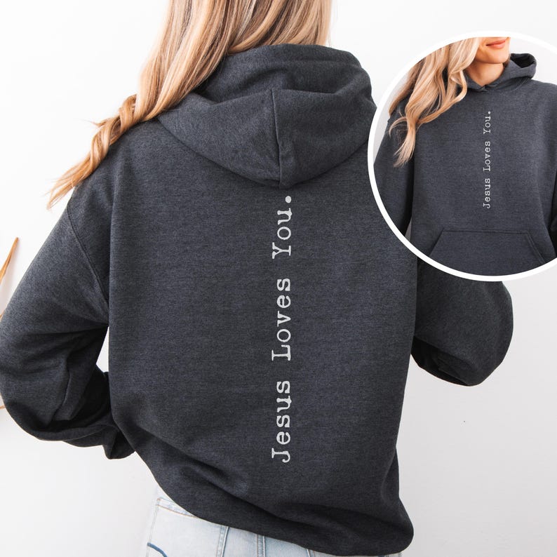 May include: Dark gray hoodie with the text "Jesus Loves You" printed vertically down the back in white. The hoodie has a hood and a front pocket. The image also includes a smaller inset of the hoodie.