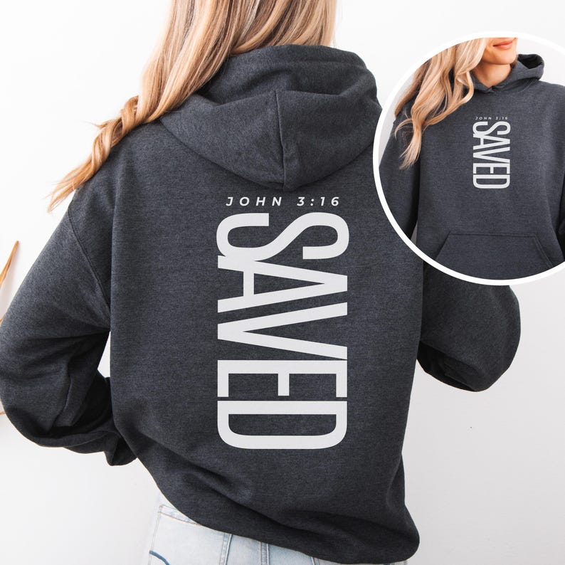 May include: Dark gray hoodie with the word "SAVED" printed vertically in large white letters on the back. The text "JOHN 3:16" is printed above the word "SAVED". A smaller image of the hoodie is in the upper right corner.