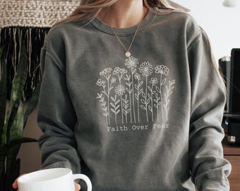 May include: A grey sweatshirt with a white floral design and the text "Faith Over Fear".