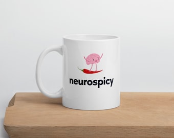 May include: White ceramic mug with a pink brain cartoon character surfing on a red chili pepper. The text "neuroscipy" is printed in blue below the image.