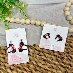 May include: Black and red polka dot bow earrings with a black silhouette design. The earrings are displayed on white cards with the text "Kathed in Blessings" and "Hypoallergenic Stainless Steel".