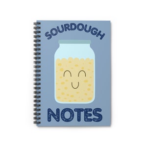 May include: A blue spiral bound notebook with the text "SOURDOUGH NOTES" in white and blue. A cartoon illustration of a jar of sourdough starter with a smiling face is in the center of the notebook.