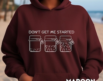 May include: Maroon hoodie with the text "DON'T GET ME STARTED" above a graphic of three jars with varying levels of contents. The word "MAROON" is printed at the bottom of the hoodie.