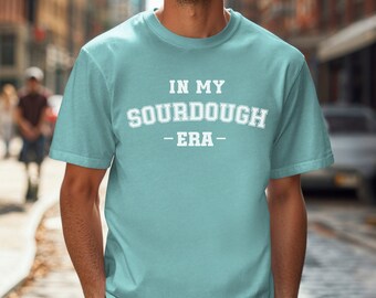 May include: A light blue t-shirt with the text "IN MY SOURDOUGH ERA" printed in white.