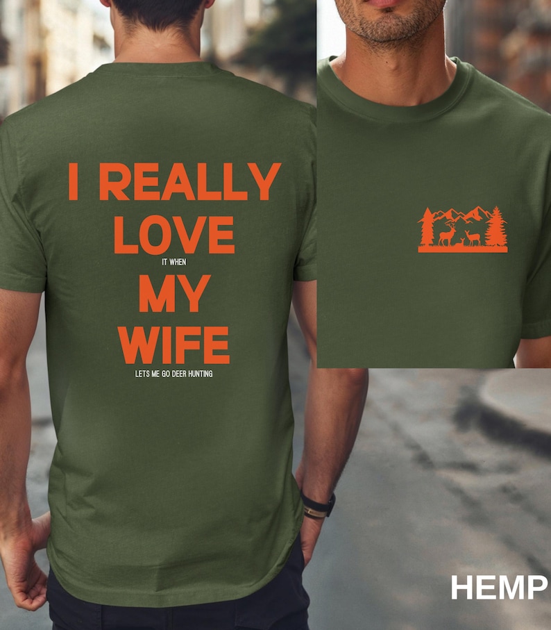 K&ouml;nnte beinhalten: Ein gr&uuml;nes T-Shirt mit dem Text "I really love my wife it when lets me go deer hunting" auf der R&uuml;ckseite. Die Vorderseite des Shirts zeigt eine Grafik mit einer Waldszene mit Hirschen.
