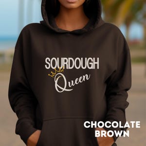 May include: A chocolate brown hoodie with the text "SOURDOUGH Queen" in white with a gold crown graphic.