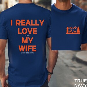 K&ouml;nnte beinhalten: Ein marineblaues T-Shirt mit dem Text "I really love my wife it when lets me go deer hunting" auf der R&uuml;ckseite und einer Silhouette eines Hirsches in einem Wald auf der Vorderseite.