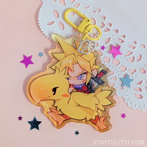 May include: A clear acrylic keychain depicting a cartoon character riding a yellow Chocobo. The keychain has a yellow clasp and a silver charm. The background includes star-shaped confetti and a decorative doily. The text "JETBYTES.ETSY.COM" is visible.