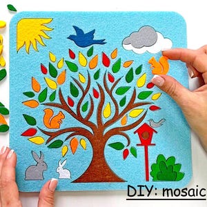 May include: A felt mosaic board with a tree design, featuring colorful leaves, squirrels, birds, and rabbits. The board is light blue with a sun and cloud. The text "DIY: mosaic" is at the bottom.