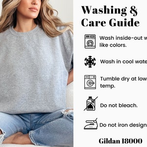 May include: Washing and care instructions for a grey sweatshirt. Wash inside-out with like colors, wash in cool water, tumble dry at low temperature, do not bleach, and do not iron the design. Gildan 18000.