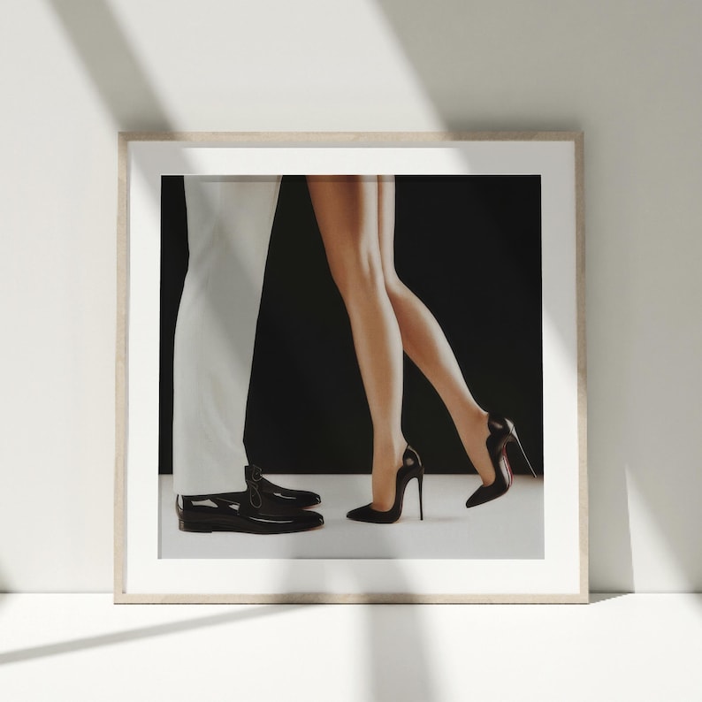 May include: A black and white photograph of a couple dancing. The woman is wearing a black dress and high heels, and the man is wearing a white suit and black shoes.