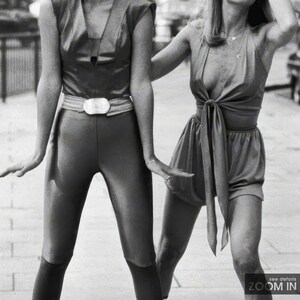Pu&ograve; includere: Due donne che indossano abiti diversi. Una donna indossa pantaloni neri e una maglietta nera con una cintura argentata. L'altra donna indossa una maglietta bianca con una gonna a fantasia bianco e nero.
