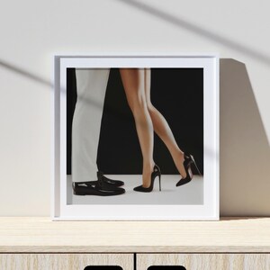 May include: A framed black and white photograph of a couple dancing. The woman is wearing a black dress and high heels, and the man is wearing a white suit and black shoes.