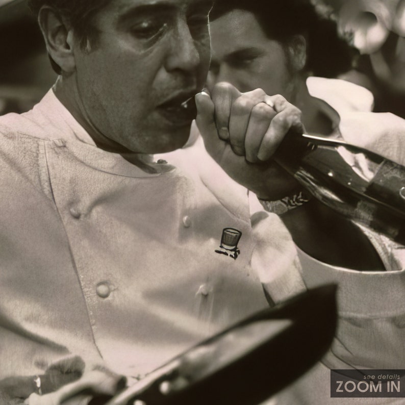 Peut inclure: Une photo en noir et blanc de deux hommes, l'un portant une veste de chef blanche avec un petit logo sur la poitrine gauche, l'autre portant un pull gris. L'homme en veste de chef regarde la cam&eacute;ra et a la bouche ouverte comme s'il parlait. L'homme en pull gris regarde l'homme en veste de chef et a la main sur le menton.