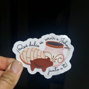 Peut inclure: Un autocollant avec une p&acirc;tisserie concha, une tasse de caf&eacute; et une petite illustration de cochon. L'autocollant porte le texte "&iexcl;Qu&eacute; dulce es servir a Jehov&aacute; junto a ti!" en &eacute;criture manuscrite. L'autocollant est blanc sur fond noir.
