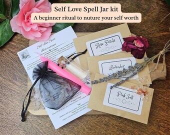 May include: A Self Love Spell Jar kit containing a pink candle, a small glass bottle, a black organza bag with crystals, and three brown paper packets labeled Rose Petals, Lavender, and Pink Salt, accompanied by an instruction sheet.