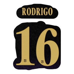 Op de afbeelding: Een zwarte sticker met de naam RODRIGO in gouden letters boven een groot nummer 16. Het getal 16 is uitgevoerd in een gouden, gestippelde textuur met een klein FC Barcelona-embleem aan de basis van elk cijfer, tegen een donkere achtergrond.