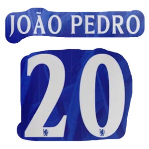 May include: A blue fabric patch with the name "JOÃO PEDRO" in white block letters. Below, a blue patch displays the number "20" in white, with a small emblem at the bottom of each digit. The patches are likely for a sports jersey.