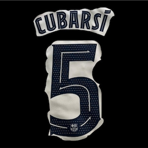 Può includere: Primo piano di una toppa bianca per maglia con il nome "CUBARSÍ" in blu navy. Sotto, un grande numero "5" blu navy, con un motivo a pois e un logo della squadra in basso.