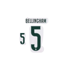Peut inclure: Un ensemble de transferts thermocollants vert foncé comprenant le nom BELLINGHAM en lettres capitales, un grand chiffre 5 et un plus petit chiffre 5. Chaque chiffre 5 comporte un petit logo circulaire du Real Madrid à sa base.