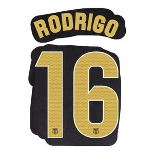 Può includere: Una grafica di maglia sportiva nera con il nome RODRIGO in lettere dorate sopra il numero 16. Le grandi cifre dorate hanno una consistenza traforata e includono un piccolo stemma del club FC Barcelona alla base di ogni numero.