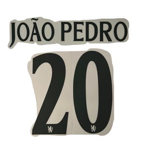 May include: A set of black and white soccer jersey numbers and name. The name "JOÃO PEDRO" is above the number "20". The number has a small emblem at the bottom. The items are on a white background.