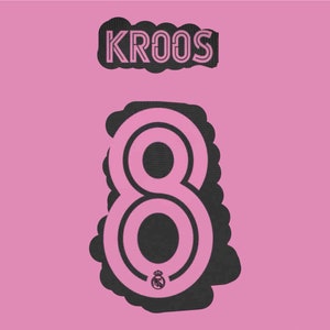 Puede incluir: Número 8 en blanco y negro con un contorno blanco y un pequeño escudo blanco en el centro. El número está sobre un fondo rosa con la palabra "KROOS" en letras blancas con un contorno negro sobre el número.