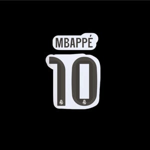 May include: A white sticker with the name "MBAPPÉ" above the number "10" in black. The number has a white interior and a black outline. The background is solid black.
