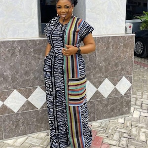 May include: A long black dress with a white pattern and colourful vertical stripes. The dress has short sleeves and a fitted waist. The colourful stripes include red, yellow, blue, and green. The dress is worn by a person.