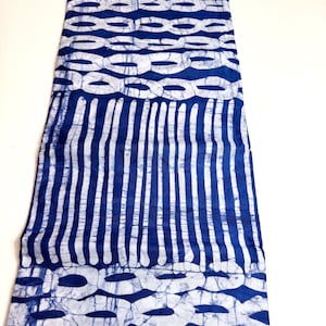 May include: A length of fabric with a blue and white pattern. The design includes vertical stripes and interconnected oval shapes. The colour scheme is a deep blue against a white background, providing a strong visual contrast.