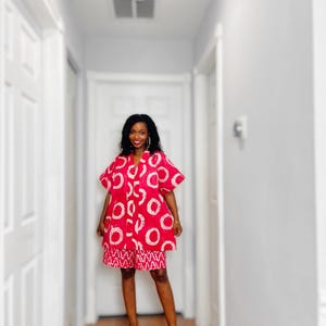 May include: A red and white patterned dress and shorts set. The dress features large white circles on a red background, with matching shorts. The outfit is paired with red sandals. The ensemble is a vibrant and eye-catching fashion statement.