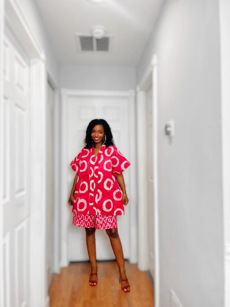 May include: A red and white patterned dress and shorts set. The dress features large white circles on a red background, with matching shorts. The outfit is paired with red sandals. The ensemble is a vibrant and eye-catching fashion statement.