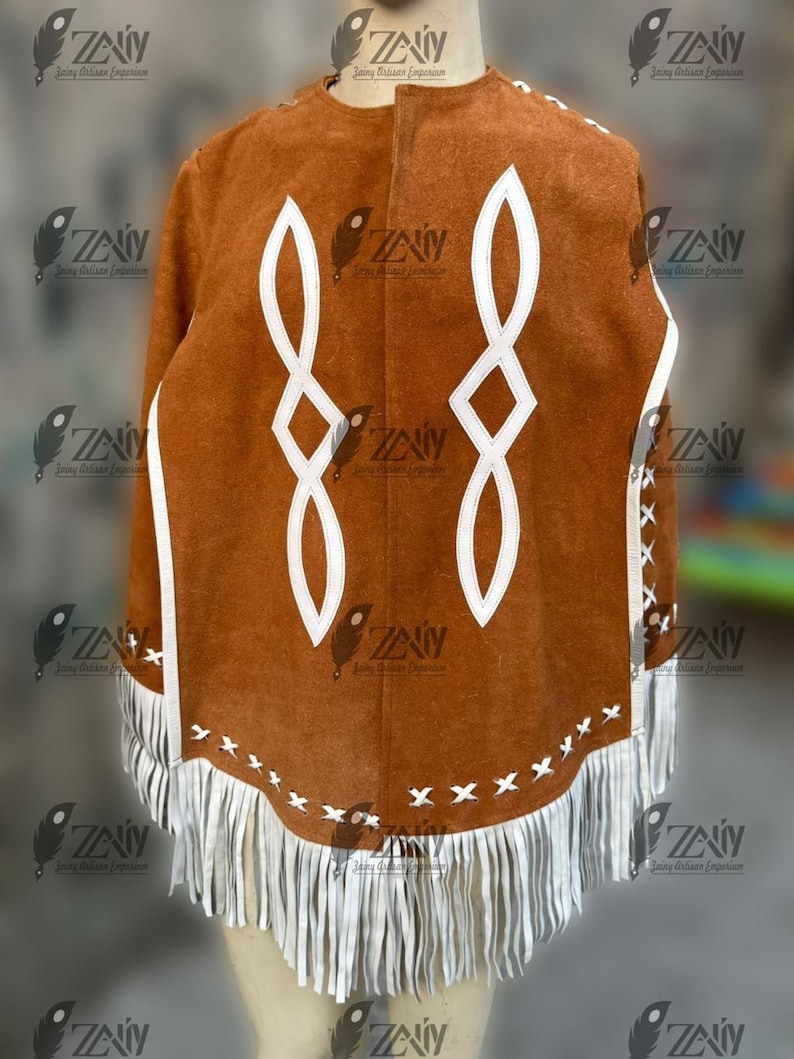 May include: A brown suede poncho with white geometric designs and fringe trim. The poncho features white accents along the edges and a series of white fringe at the bottom. The design includes two large, stylized white infinity symbols.