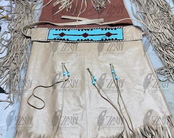May include: A tan leather dress featuring long sleeves with extensive fringe detailing, a brown chest panel, and a matching belt with a bright turquoise and dark red geometric beaded pattern. The garment includes decorative leather ties with blue and white beads.