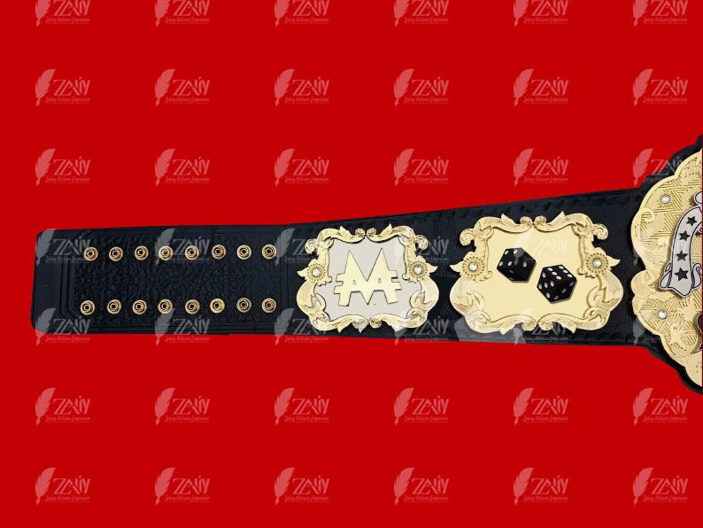 May include: A black leather championship belt with gold accents. The belt features a large, silver plate with the letters "AA" in the center. The belt also has a smaller gold plate with two dice on it.