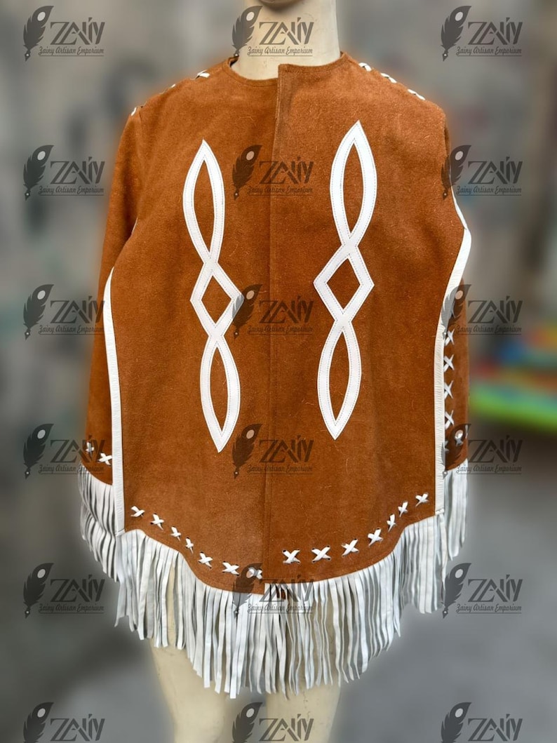 May include: A brown suede poncho with white geometric designs and fringe trim. The poncho features white accents along the edges and decorative stitching. The design includes a series of white, stylized infinity symbols.