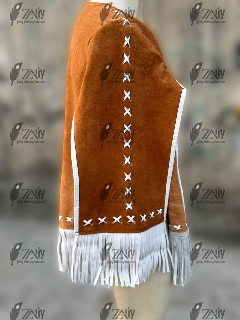 May include: A brown suede jacket with white fringe and accents. The jacket features white stitching details and a white trim. The sleeves have fringe at the cuffs. The jacket is a unique piece of apparel.