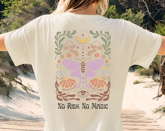 May include: A white t-shirt with a colorful graphic design featuring a butterfly, flowers, mushrooms, and a crescent moon. The text "No Risk No Magic" is printed below the design.