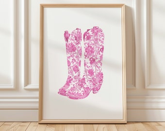 May include: A framed print of a pair of pink cowboy boots with a floral pattern. The boots are set against a white background.