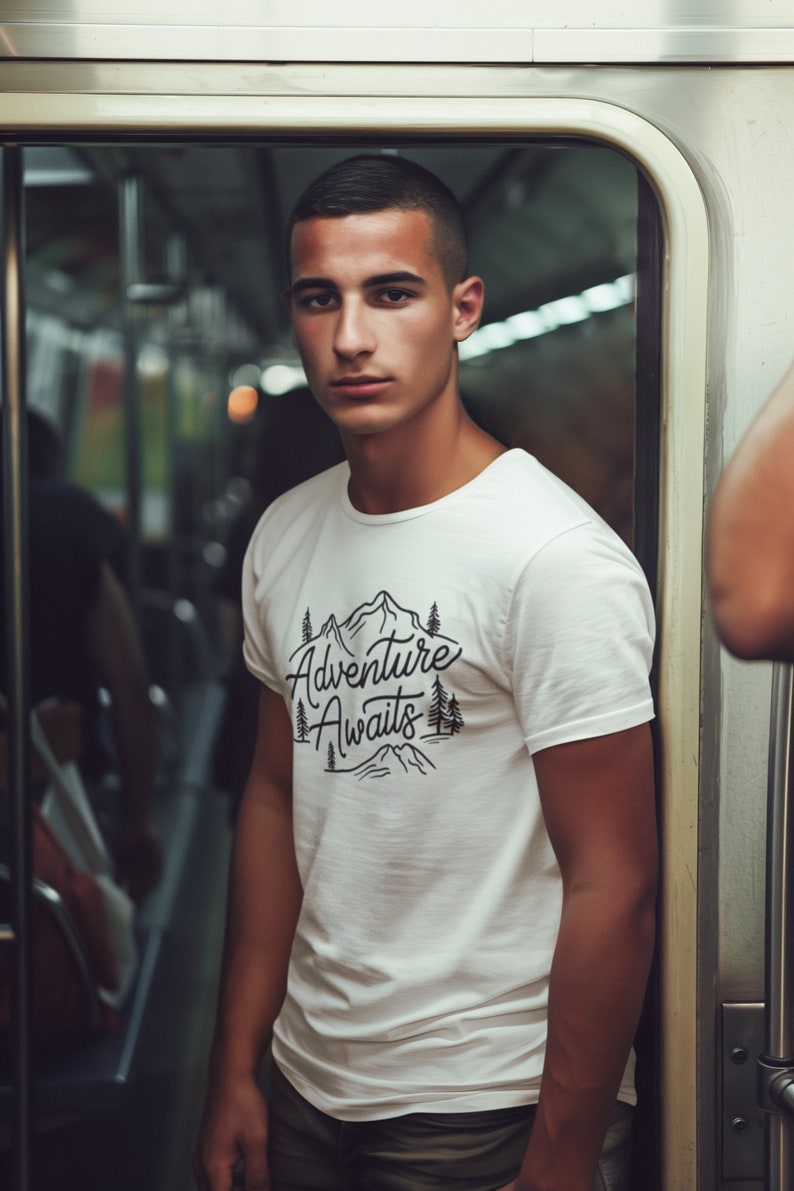 Puede incluir: Una camiseta blanca con un gr&aacute;fico negro de monta&ntilde;as y &aacute;rboles. El gr&aacute;fico dice "Adventure Awaits".