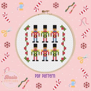 May include: A cross stitch pattern featuring six nutcracker soldiers in a row. The soldiers are wearing red and green uniforms with black hats and white trim. The pattern is surrounded by a border of red and green holly.