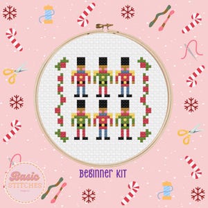 May include: A beginner cross stitch kit featuring a design of six nutcracker soldiers in a row. The kit includes embroidery floss, a needle, and a hoop.