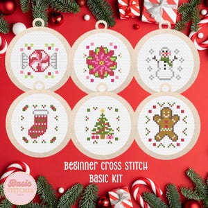 May include: Six round cross-stitch ornaments with Christmas-themed designs. The designs include a candy cane, poinsettia, snowman, stocking, Christmas tree, and gingerbread man. The ornaments are on a red background with greenery and candy canes. The text "Beginner Cross Stitch Basic Kit" is visible.