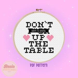 Puede incluir: Un aro de bordado blanco con texto negro que dice "DON'T  UP THE TABLE" con dos corazones rosas. El texto "SWIPE TO REVEAL" está escrito en una fuente más pequeña sobre la palabra "UP".